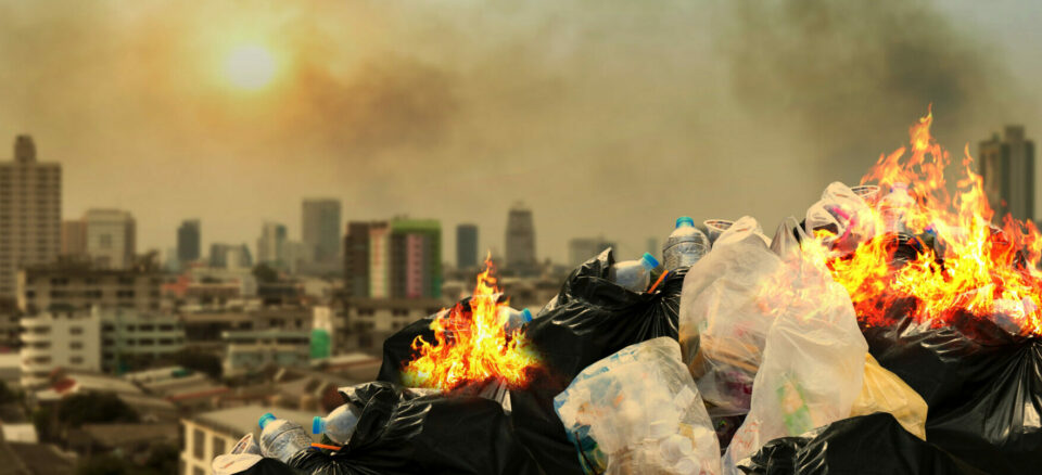 Garbage pile on fire with city in the background