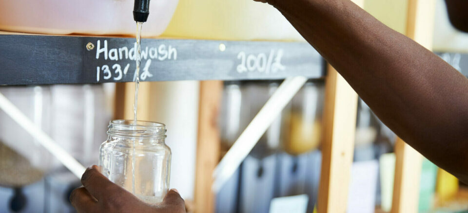 Man Filling Container From Dispenser For Body And Beauty Products In Plastic Free Grocery Store