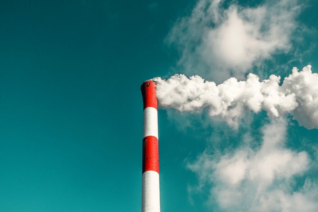 Red and white striped smoke stack emitting pollution.