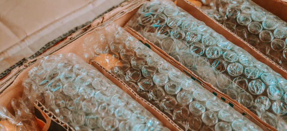 Cardboard box with products inside wrapped in plastic bubble wrap.