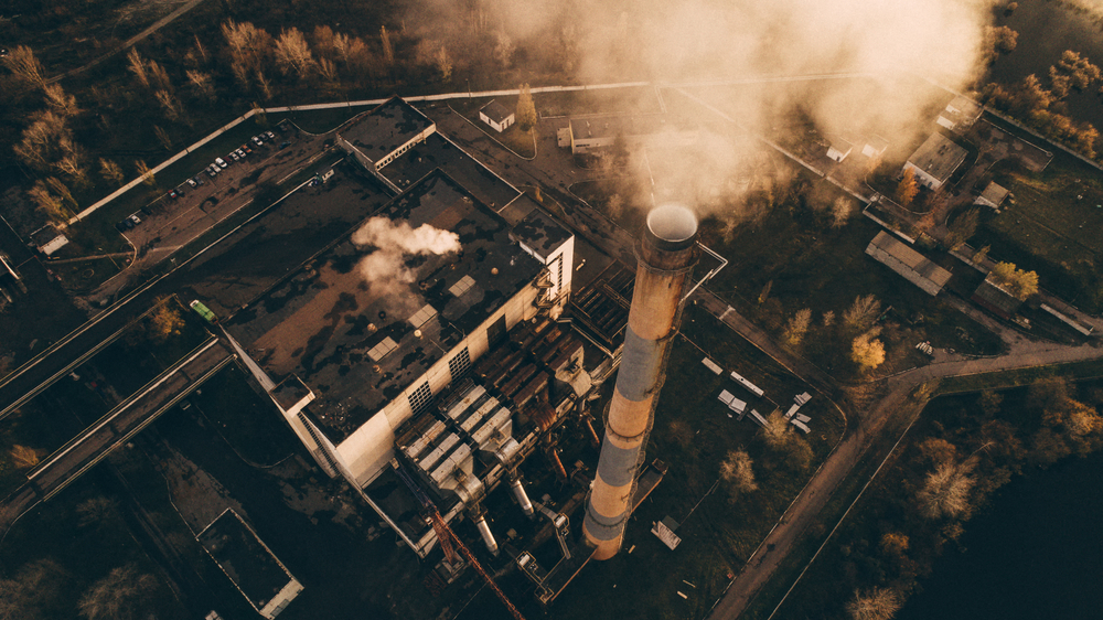 Waste incinerator plant with smoking smokestack. The problem of environmental pollution by factories. Photo: RONEDYA via Shutterstock