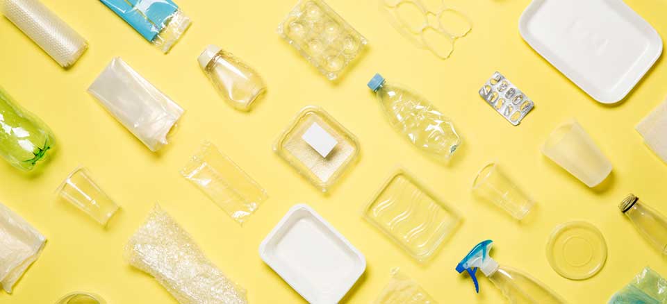 Different types of used plastic packaging arranged on a yellow background