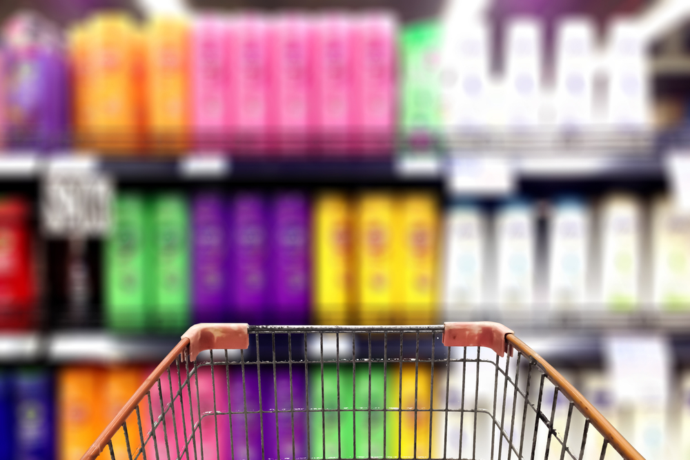 Shopping cart in front of display of plastic haircare products.