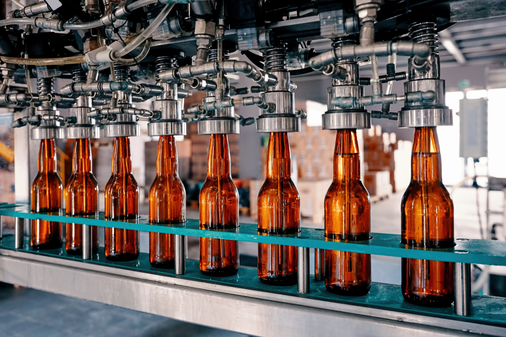 Glass bottles being filled on a conveyor belt in a factory.