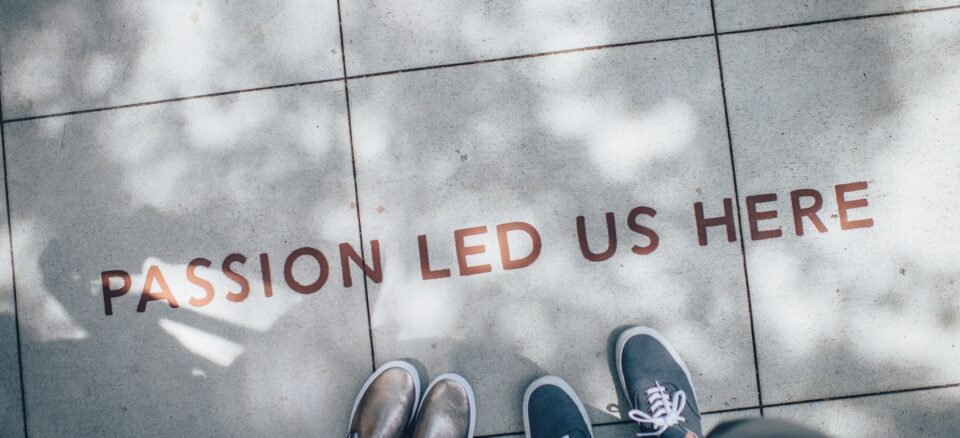 Two people standing on sidewalk looking down at the words "passion led us here."