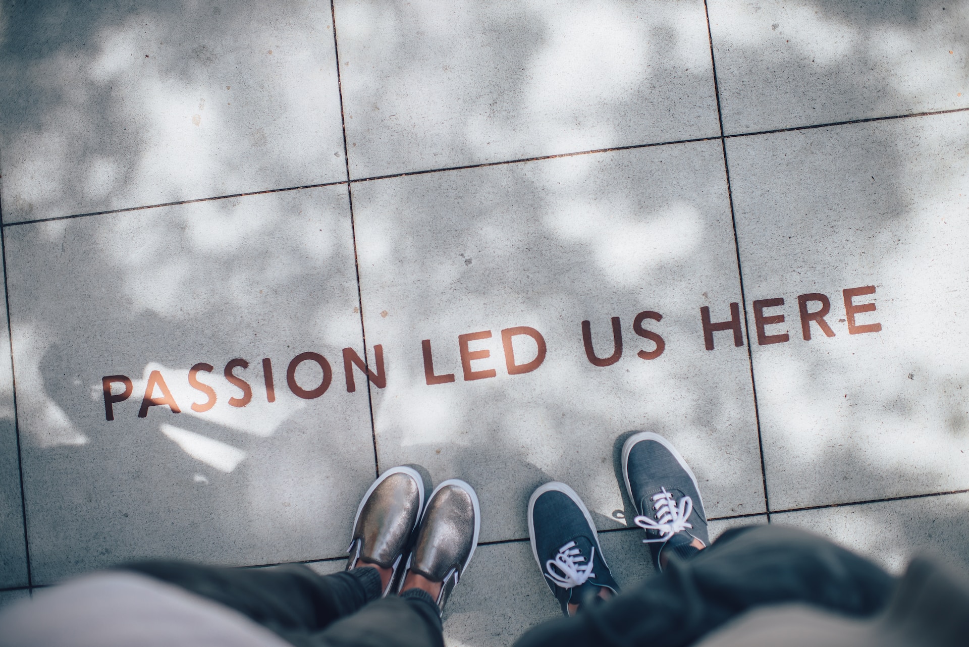 Two people standing on sidewalk looking down at the words "passion led us here."