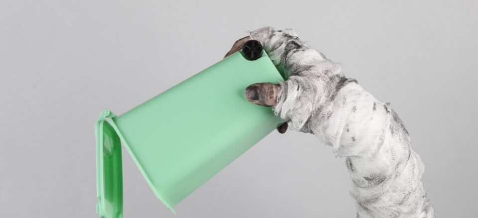 Monster's hand wrapped in a bandage holding trash can isolated on gray background.